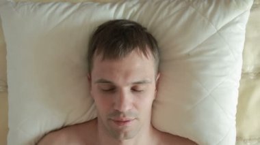Bir adam bir huzursuz uyku ile bir yatakta uyuyor. Akşamdan kalma uyanış. Yakın çekim. Yukarıdan görüntülemek