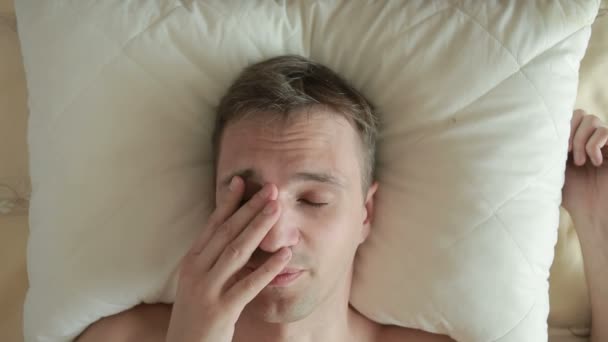 Un hombre está durmiendo en una cama con un sueño inquieto. Despertando de una resaca. Primer plano. Vista desde arriba — Vídeo de stock