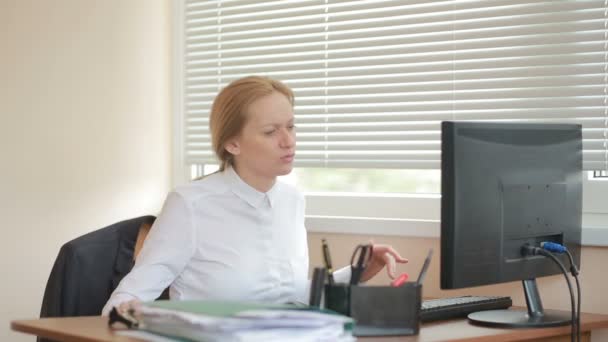 Женщина-менеджер устала от работы, занимаясь физическими упражнениями за столом в офисе — стоковое видео