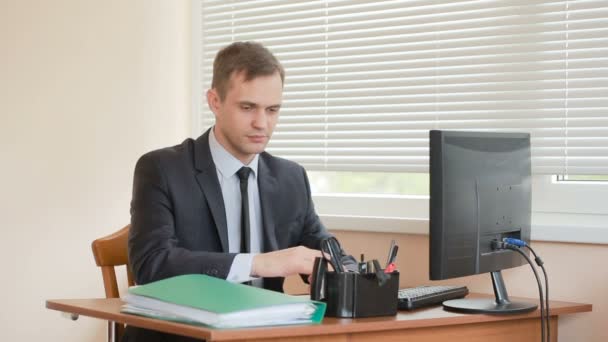 El gerente de la oficina se sienta a la mesa cansado del trabajo. Las manos están temblando. — Vídeos de Stock