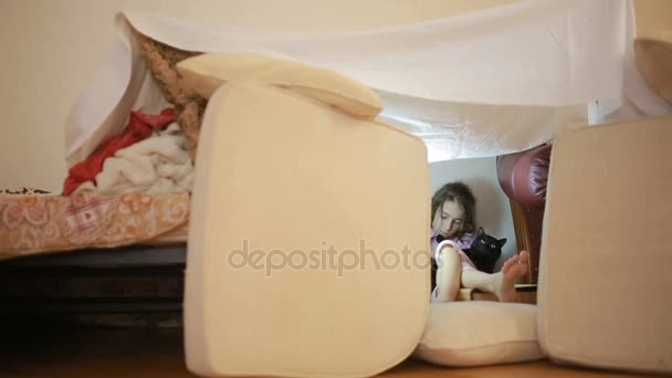 Malá holka sedí v provizorní rodu polštáře a deky dům — Stock video