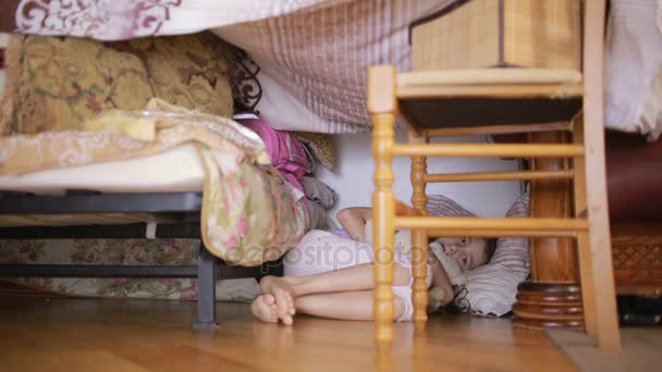 A little girl is sitting in a makeshift house of pillows and a blanket house — Stock Video