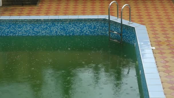 Chuva forte cai em uma piscina. Não temporada, piscina abandonada suja — Vídeo de Stock