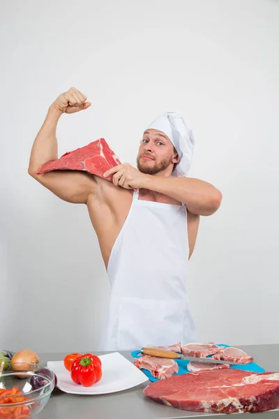 Kulturista šéfkuchař připravuje velké kusy syrového masa. přírodní proteiny — Stock fotografie