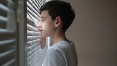 Çocuk sokakta kör pencereden görünüyor