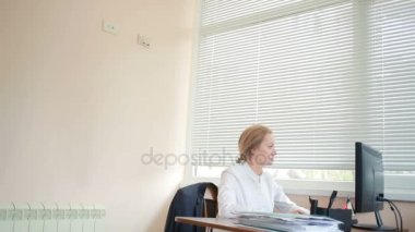 Bir bilgisayar ve Office belgeleri ile çalışan çekici kadın