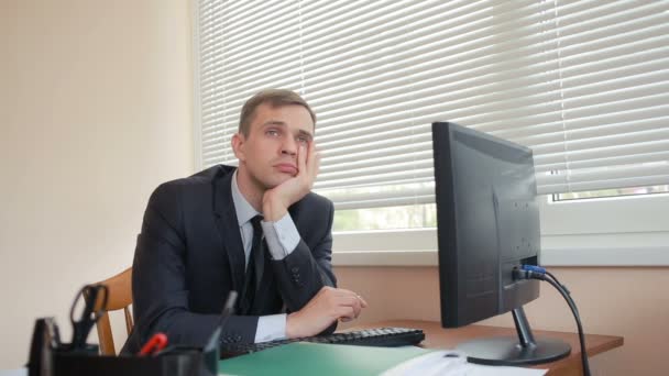 Менеджер в офисе сидит за столом устал от работы — стоковое видео