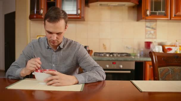 Man eats rice and cutlet in his kitchen at home — Stock Video