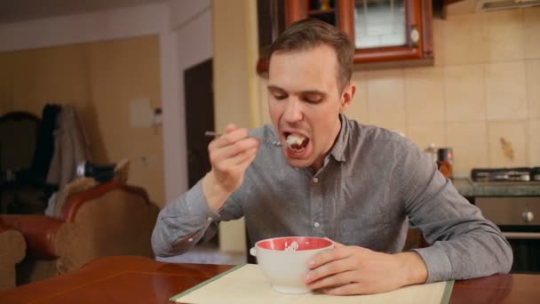 Man eet rijst en kotelet in zijn keuken thuis — Stockvideo