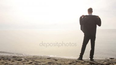 İşadamı elbiseli bir plaj boyunca elini kolunu sallaya dönüyor. güzel plaj hayran