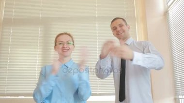 İki işadamı erkek ve kadın panjurlar bir pencere zemin üzerine bir ofiste alkışlar. Alkış