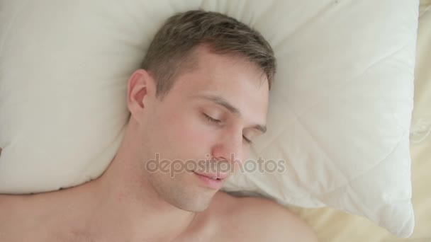 Un homme se couche sur un lit et ronfle dans un rêve. Gros plan. Vue d'en haut — Video