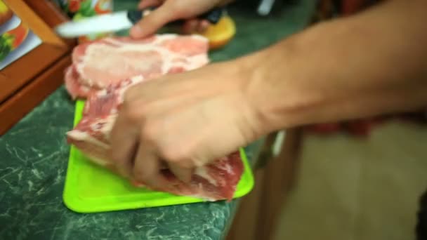 Männliche Hände schneiden rohes Fleisch auf Steaks auf einem Schneidebrett. Nahaufnahme. — Stockvideo