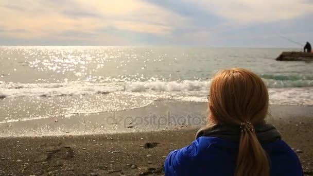 Una mujer se sienta sola en una playa desierta con mal tiempo, mira al mar y come pizza — Vídeos de Stock