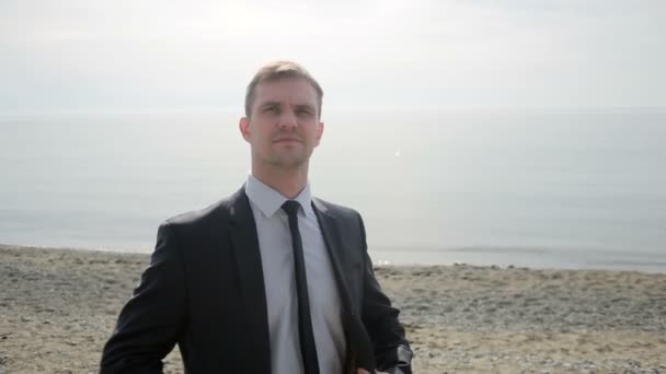 Businessman strolls along the beach in a suit . admires the beautiful beach — Stock Video