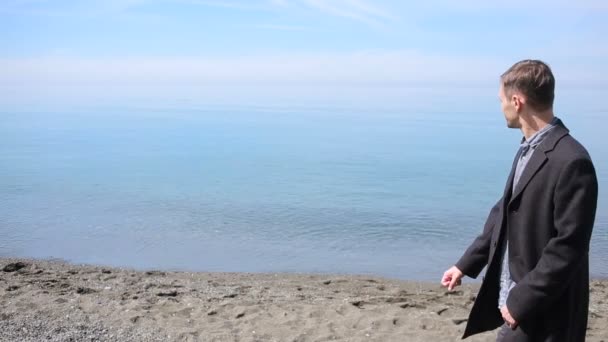 Uomo d'affari passeggia lungo la spiaggia con un completo. ammira la bellissima spiaggia — Video Stock