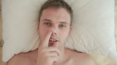 Adam yatakta yatıyor ve parmağını burnuna, alır yakın çekim. Yukarıdan görüntülemek