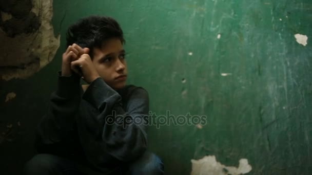 The boy is sitting on the steps of an abandoned porch. The concept of childrens drug addiction, vagrancy, homelessness. — Stock Video