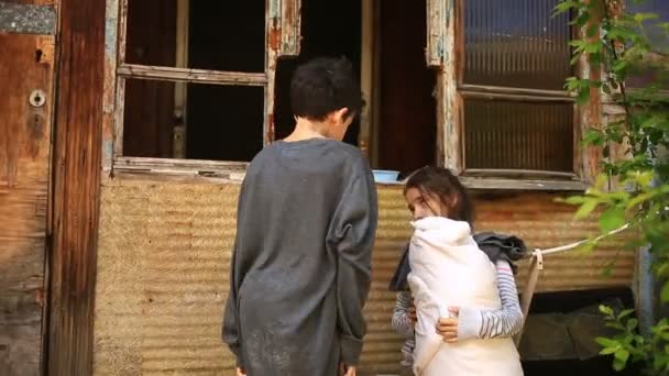 Niños refugiados con un bebé en brazos en el fondo de casas bombardeadas. Guerra, terremoto, fuego — Vídeo de stock