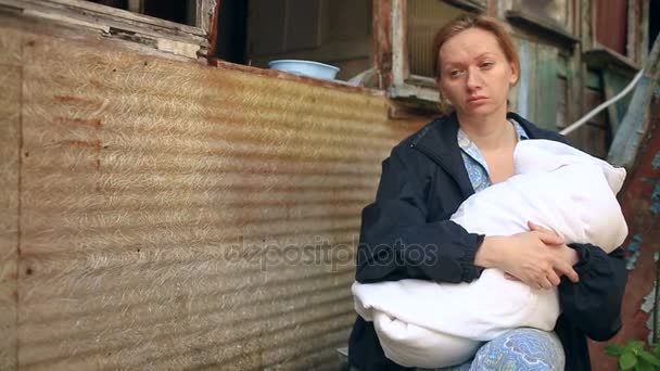 Femme épuisée, mère avec un bébé dans les bras sur le fond des maisons bombardées. Guerre, tremblement de terre, incendie — Video