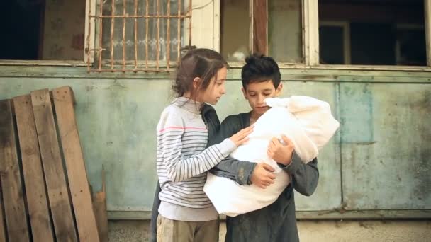 Děti uprchlíků s dítětem v náručí na pozadí bombardován domů. Válka, zemětřesení, požár — Stock video