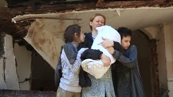 Παιδιά προσφύγων και τους μητέρα με ένα παιδί στην αγκαλιά στο φόντο των βομβαρδισμένα σπίτια. Πόλεμος, σεισμός, πυρκαγιά — Αρχείο Βίντεο