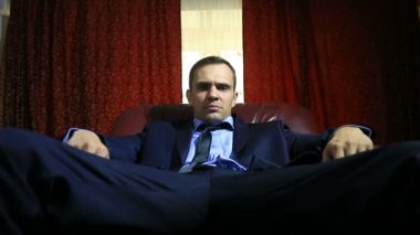Zalim bir adam bir takım elbise içinde oturan bir deri koltukta, o mutlu değil, o jestleri hiçbir ve emekli olmak sorar