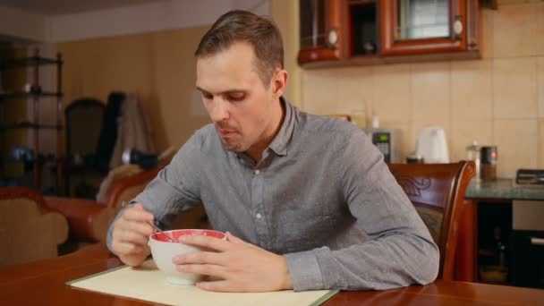 Ο άνθρωπος τρώει ρύζι και κυμά στην κουζίνα του στο σπίτι — Αρχείο Βίντεο