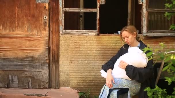 Kimerült nő, anya a csecsemő a karján, a háttérben a lebombázott házak. Háború, földrengés, tűz — Stock videók