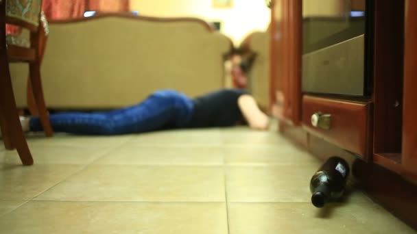 Alkoholfogyasztás, palackkal kezében nő nő. Üres üveg alkohol alatt a háttérben, egy asszony feküdt a padlón. — Stock videók