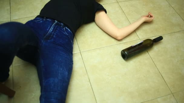 Vrouw drinken van alcohol, vrouw met fles in handen. Lege fles alcohol onder de achtergrond van een vrouw liggend op de vloer. — Stockvideo
