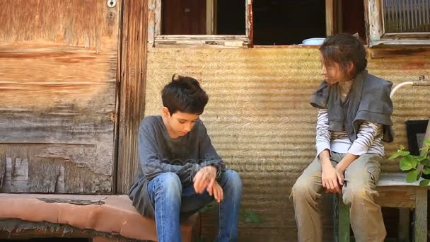 I bambini rifugiati sono seduti vicino a una casa in rovina. Guerra, terremoto, fuoco, bombardamenti — Video Stock