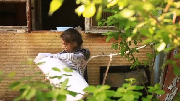 Niños refugiados con un niño en brazos en medio de casas destruidas. Guerras, terremotos, incendios, bombardeos. La niña sostiene en sus brazos a su hermano o hermana en el pecho — Vídeo de stock