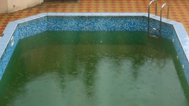 Las fuertes lluvias caen en una piscina. No es temporada, piscina sucia abandonada — Vídeo de stock