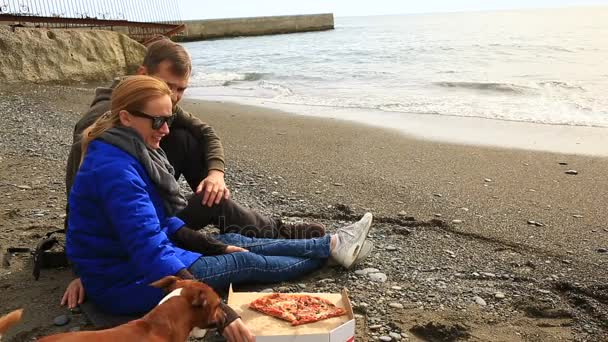 Paar isst Pizza am Strand, kaltes Wetter, zusammen — Stockvideo