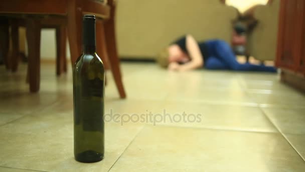 Kvinde drikker alkohol, kvinde med flaske i hænderne. Tomme flaske alkohol under baggrunden af en kvinde liggende på gulvet . – Stock-video