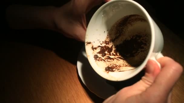 Adivinhar na área do café, uma mão feminina segurando uma caneca de café com motivos de café. Close-up . — Vídeo de Stock