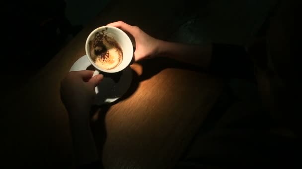 Adivinhar na área do café, uma mão feminina segurando uma caneca de café com motivos de café. Close-up . — Vídeo de Stock