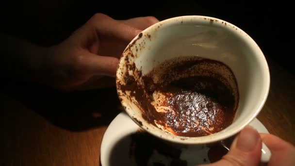 Adivinhar na área do café, uma mão feminina segurando uma caneca de café com motivos de café. Close-up . — Vídeo de Stock