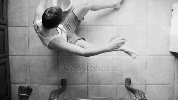 En man tvättar golvet i köket medan du sitter på golvet. Doppa en trasa hink, ovanifrån. Svartvit bild — Stockvideo