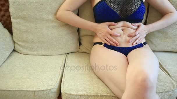 A woman is a fat stomach. Overweight and weight loss concept. A girl in a bathing suit pulls the skin on her stomach, which is stretched and flabby after losing weight or giving birth to a baby — Stock Footage A woman is a fat stomach. Overweight and weight loss concept. A girl in a bathing suit pulls the skin on her stomach, which is stretched and flabby after losing weight or giving birth to a baby Stock Footage