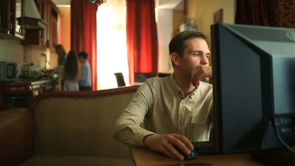 Der Ehemann frustriert am Computer zu Hause arbeitet, während seine glücklichen Kinder und seine Frau gemeinsam in der Küche kochen — Stockvideo