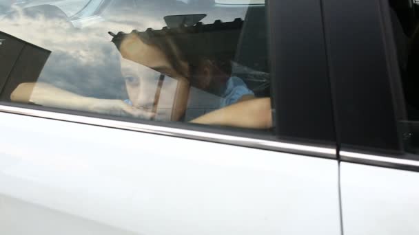 Mała dziewczynka, znudzona w samochodzie - wyglądająca przez okno - odbicie uliczne — Wideo stockowe