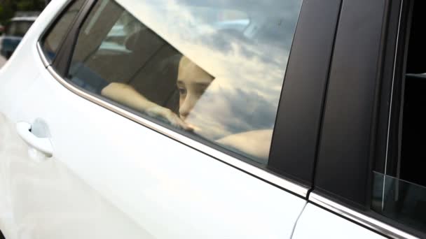 Menina, entediada no carro - olhando pela janela através da janela - reflexão de rua — Vídeo de Stock