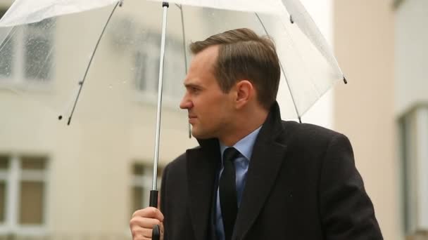 Sfrustrowany przez pogodę, stojąc pod parasolem podczas deszczu. Nieszczęśliwy człowiek w garniturze — Wideo stockowe