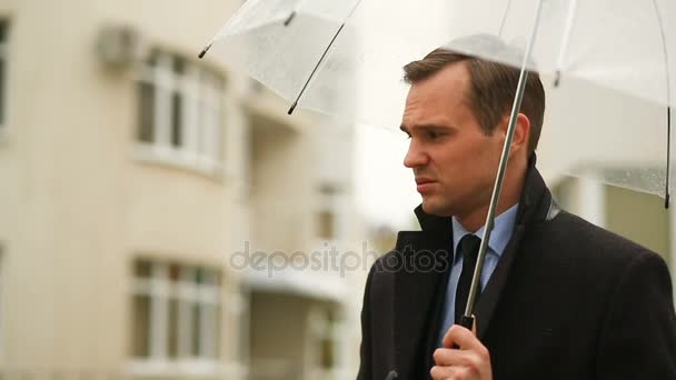 Frustrasi oleh cuaca, berdiri di bawah payung selama hujan. Pria yang tidak bahagia dalam setelan jas — Stok Video