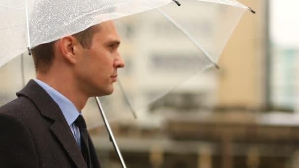 Απογοητευμένος από τις καιρικές συνθήκες, που στέκεται κάτω από την ομπρέλα κατά τη διάρκεια της βροχής. Δυστυχισμένος άνθρωπος σε ένα κοστούμι — Αρχείο Βίντεο