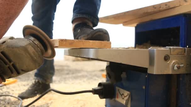 Close up van handen van mannelijke timmerman holding grinder en vloeiend maken houten bord in cirkelvormige bewegingen — Stockvideo