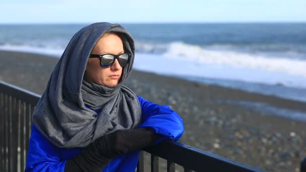 Una chica con gafas de sol mirando una tormenta se para en el paseo marítimo — Vídeo de stock