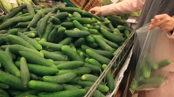 Een vrouw in een supermarkt kopen van groenten, komkommer — Stockvideo